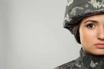 Pretty female soldier on grey background, closeup