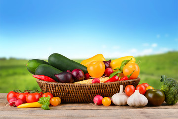 Fresh vegetables on wooden table against nature background