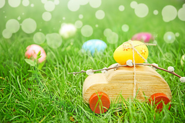 Wooden toy car with Easter egg on green grass