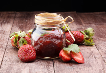 Strawberry jam in a jar on wooden background