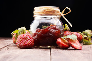 Strawberry jam in a jar on wooden background