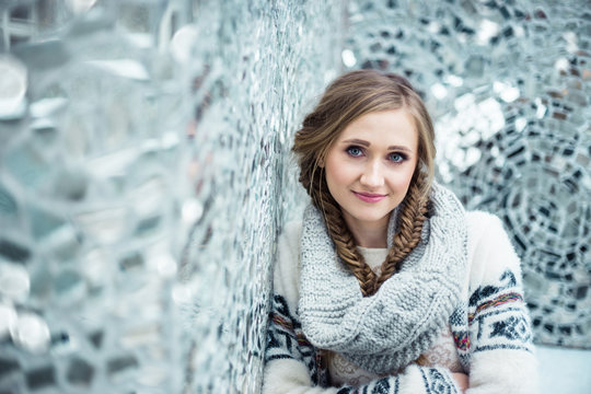 Winter portrait of a girl in braids against wall of shattered mirrors in Rosa Pasage in Lodz, Poland.