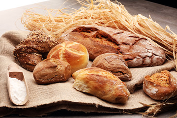 Different kinds of bread rolls on black board from above. Kitchen or bakery poster design.