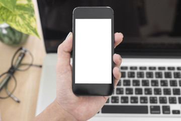 Business hand holding smart phone with white screen isolated on desk office background.