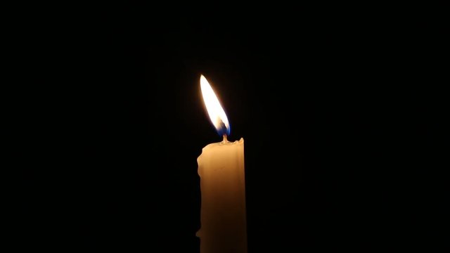 lit candle on the black background
