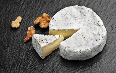 Camembert cheese with nuts on dark slate background