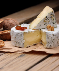 Camembert (close-up shot) with nuts,raisins and on rustic wooden background.selective focus