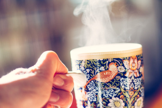 Dampfende Teetasse mit mit kunstvollem Muster gehalten von M&auml;nnerhand