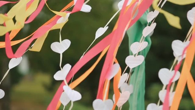 Wind blows colorful ribbons and paper hearts hanging from wedding altar