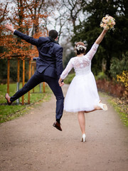 Ehepaar, Brautpaar von hinten springt auf einem Weg mit Brautstrauß in der Hand