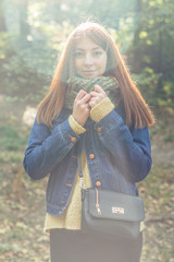 A girl stands on the backlit and looking at the camera in a forest.