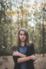 Portrait of a girl in a forest and falling leaves.