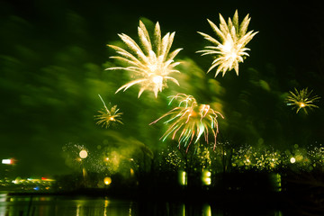Abstract, blurry, bokeh-style colorful photo of fireworks above the river in New Year