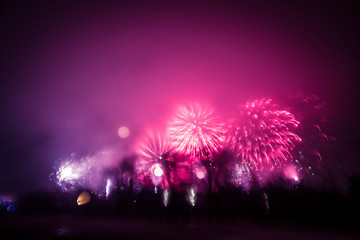 Abstract, blurry, bokeh-style colorful photo of fireworks above the river in New Year