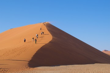 Fototapeta na wymiar Namib-Naukluft National Park, Namibia - August 2016: Visitors walking up Dunes 45