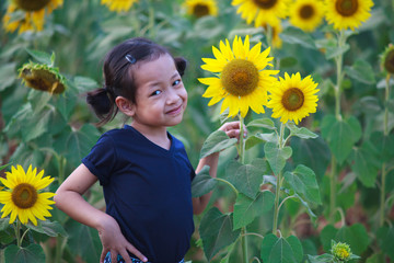 Cute child smiling in the sunflower field.