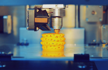 3d printer printing objects yellow form closeup. Modern technical 3D printing.