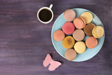 Macarons, coffee, and paper butterfly on purple