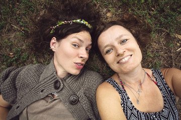 Fototapeta premium Young women laying in grass, loving nature, taking selfie