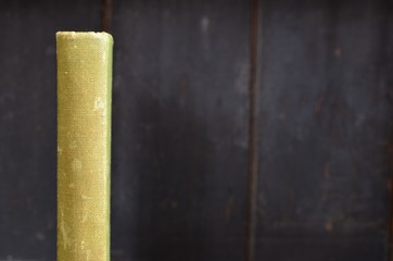 Green antique book spine on old wooden bookshelf background