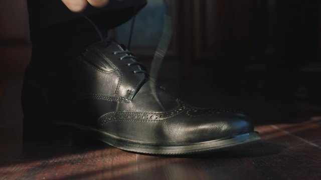 Man tying laces on black shoes
