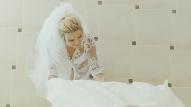 Blonde Bride admires her wedding dress. View from above