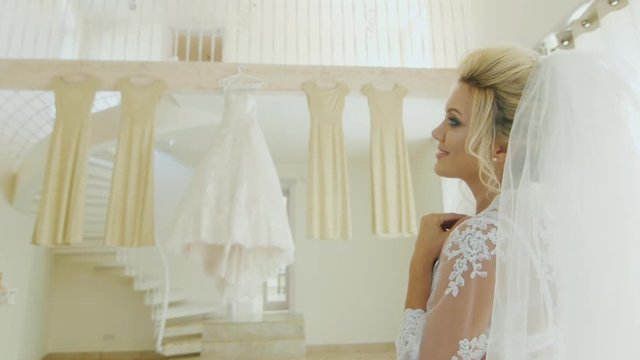 Attractive Caucasian bride looks at her wedding dress and bridesmaids' dresses. Rear view over the shoulder