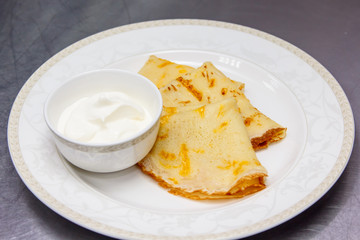 Russian pancakes with sour cream are on the plate.