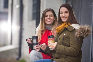 Happy girlfriends  having fun with coffee takeaway cup in winter season