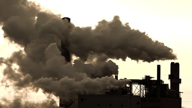 Factory smokestacks contributing to climate change, pouring out massive volumes of steam or smoke into the atmosphere.