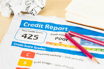 Poor credit score report on wrinkled paper with pen and calculat