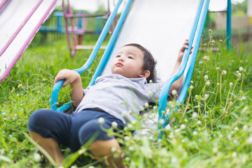 Little Asian kid playing slide at the playground