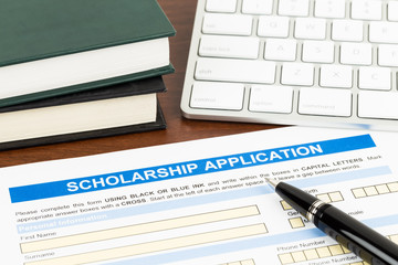 Scholarship application form with pen, keyboard, and text book