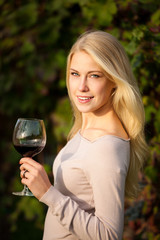 Woman drinks red wine in vineyard