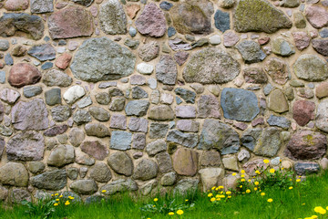 eine Natursteinmauer mit Wiese und Blüten