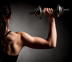 Fototapeta na wymiar Atractive fit woman works out with dumbbells as a fitness concep