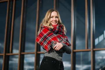 Happy woman with a scarf. Autumn. Autumn portrait of the beautiful girl. Office building. Fashionable portrait of a girl model with waving red scarf. Autumn portrait in the city.