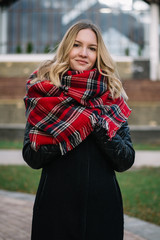 Happy woman with a scarf. Autumn. Autumn portrait of the beautiful girl. Office building. Fashionable portrait of a girl model with waving red scarf. Autumn portrait in the city.