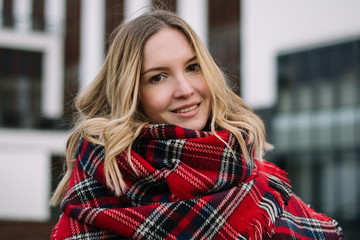 Happy woman with a scarf. Autumn. Autumn portrait of the beautiful girl. Office building. Fashionable portrait of a girl model with waving red scarf. Autumn portrait in the city.