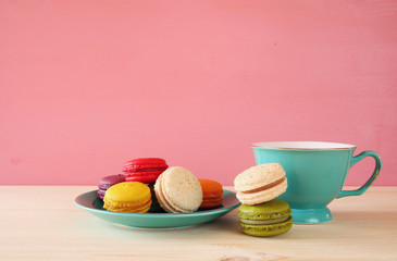Cup of coffee and colorful macaron on wooden table