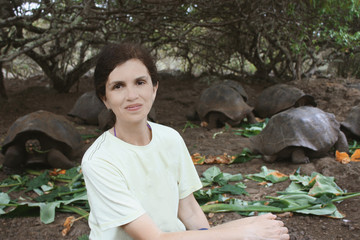 mid age smiling woman sitting near galapagos turtles