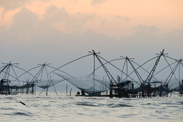 Fototapeta na wymiar Silhouette of traditional fishing method using a bamboo square dip net with sunrise sky background,livelihoods of fishermen at Pakpra, Phattalung in Thailand