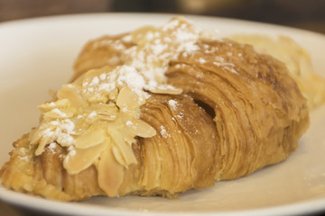 Croissant almond bread on white dish in morning breakfast.