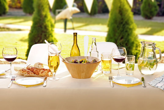 Table with food and drinks served for picnic in garden