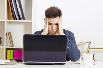 young man in front of the computer laptop concentrated or overwhelmed
