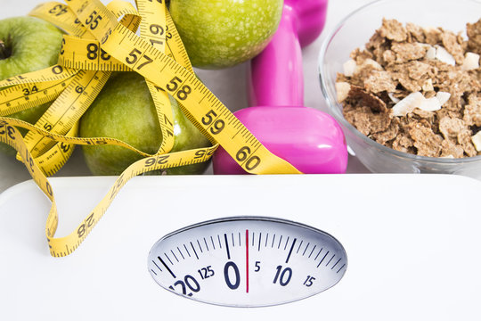 scale with cereals, fruit, weight and tape measure and concept of diet and healthy lifestyle