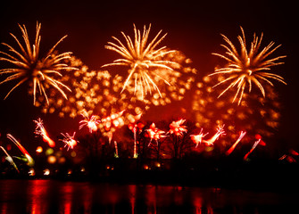 Fototapeta na wymiar Abstract, blurry, bokeh-style colorful photo of fireworks above the river in New Year