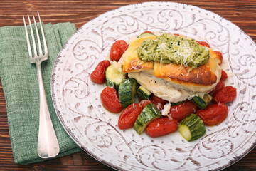 Tasty baked chicken breasts which basil pesto sauce, tomatoes, and cheese. Healthy eating concept.