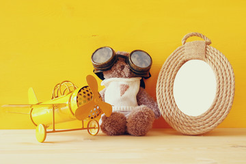 vintage toy plane and cute teddy bear next to empty frame