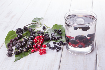 Mulberry berries, blackberries and currants detox water on white wooden table